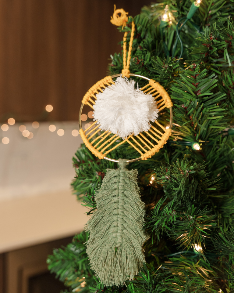 Yellow and green macrame dream catcher hanging in a Christmas tree
