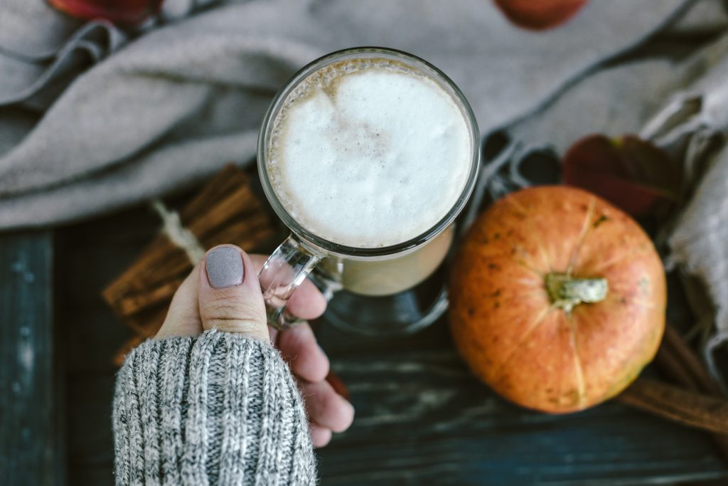 Spicy pumpkin latte on a wooden board with a sweater