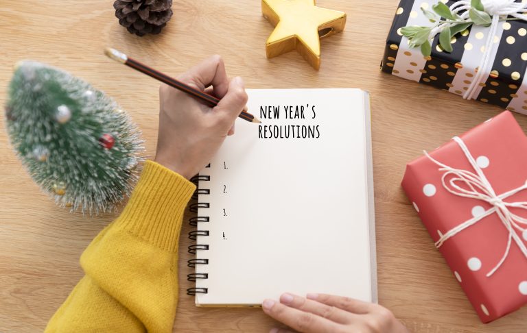 Woman hand writing New year's resolution on note paper in new year