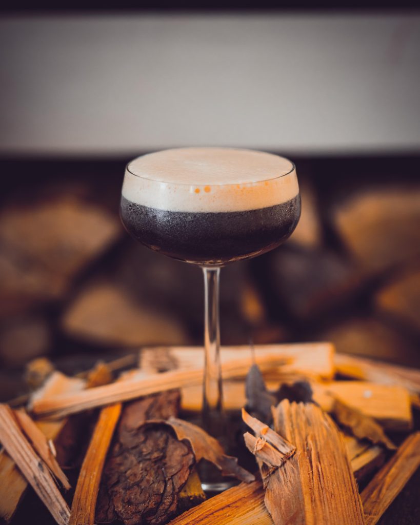 Vertical shot of a glass of delicious espresso martini on the table with a blurry background