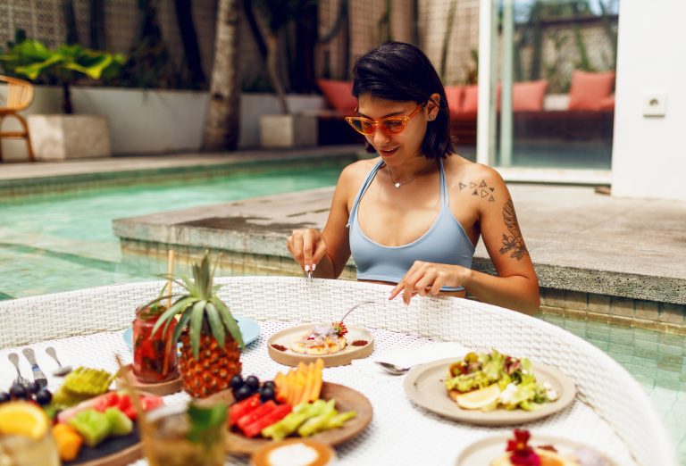 Young woman having breakfast by the pool