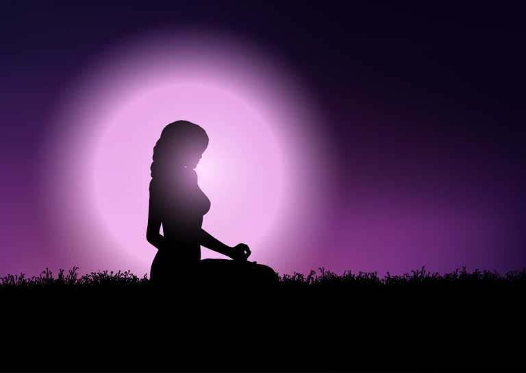 Silhouette of a female in a yoga position against a sunset sky