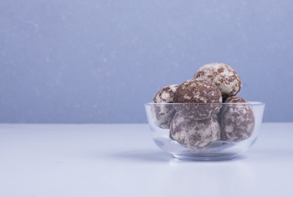 Bliss balls in a glass cup on blue backdrop on the right side.