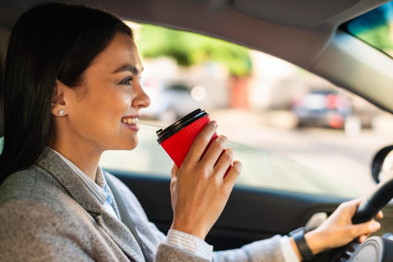 Women drinking coffee in a to-go cup while driving