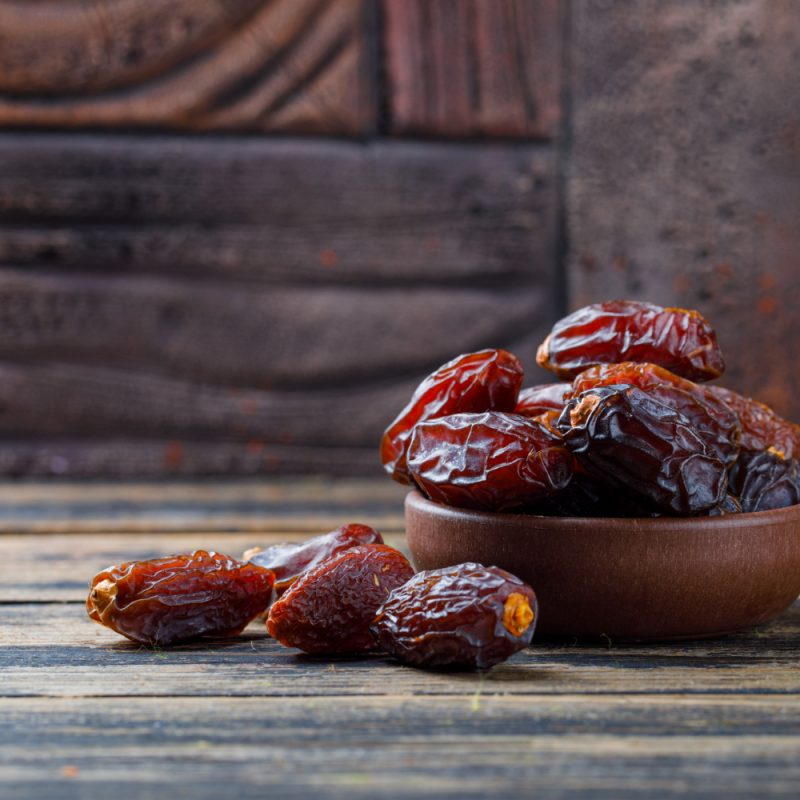 Dates in a clay bowl on a wood table