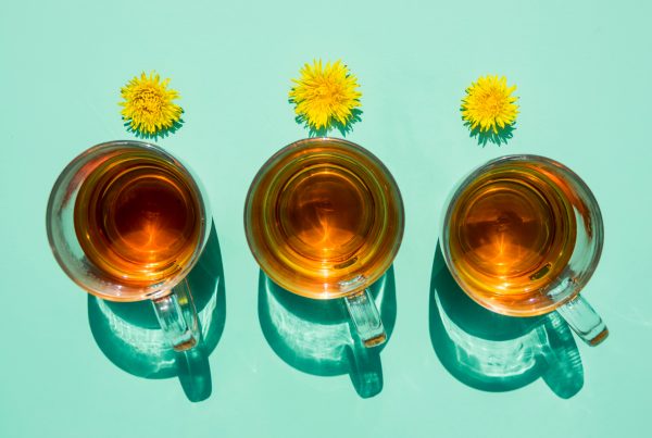 3 tea cups on a light green background with dandelion flowers