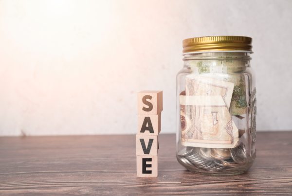 Glass jar with money and the word save in blocks