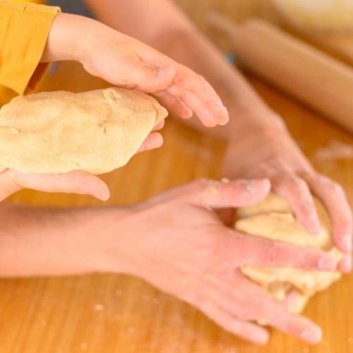 Parent and child hands making dough