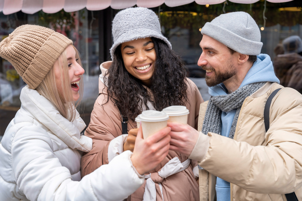 Friends in winter coats enjoying a hot beverage outside together