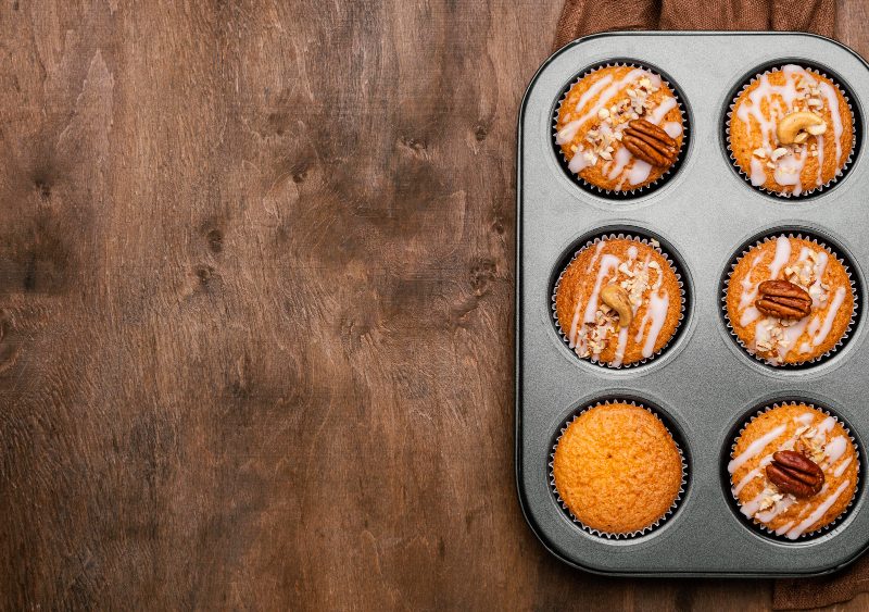 Pumpkin muffins in a baking tray on a wood table top