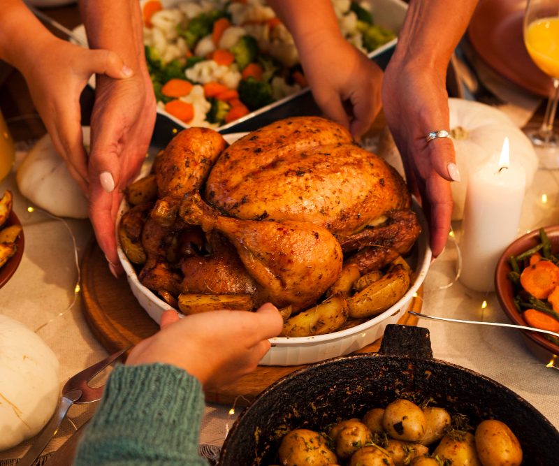 Close up of hands serving a turkey at a dinner table