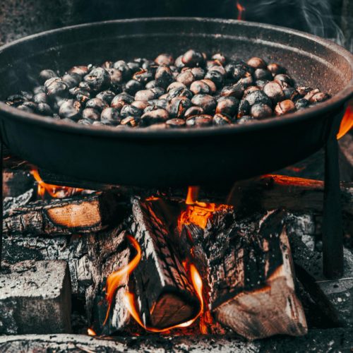 Chestnuts roasting in a cast iron pan on a fire