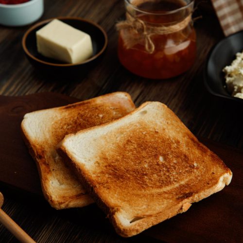 Toast on a table with a jar of honey and stick of butter