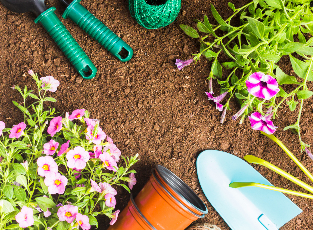 Garden tools in soil next to flowers