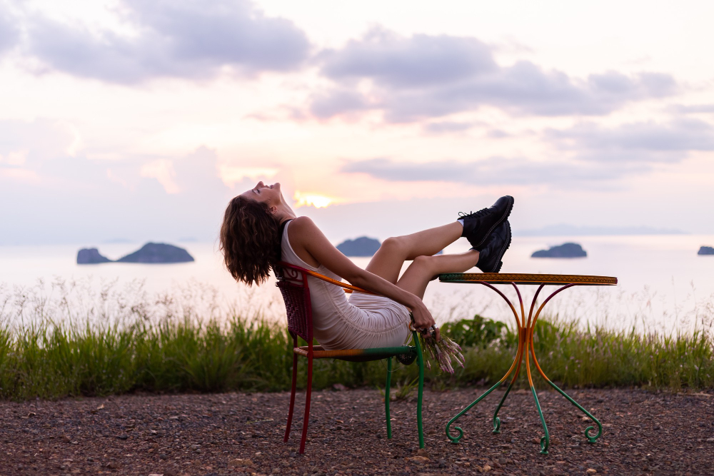 woman relaxing in a chair near the ocean at sunset