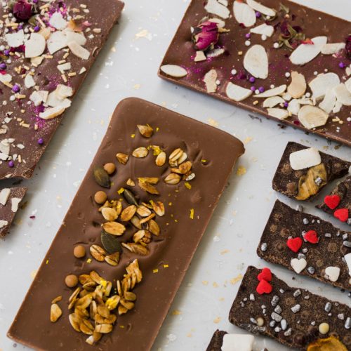 Chocolate bars with different toppings on white table