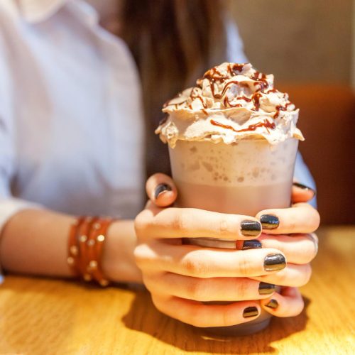 Woman holding an iced drink with whipped cream