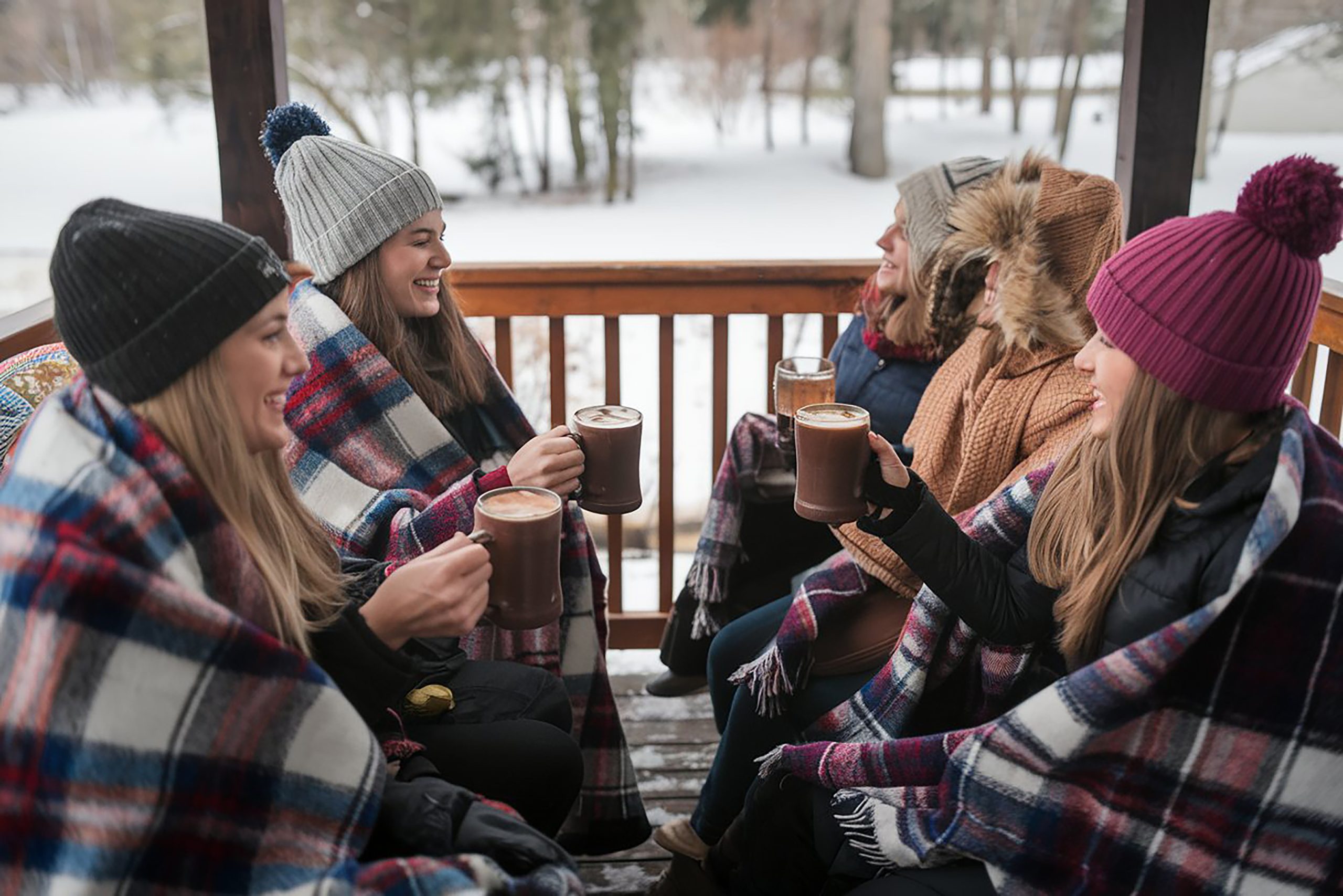 Group of friends on back porch wearing blankets and drinking a hot beverage