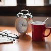 Alarm clock on a table with coffee cup and reading glasses