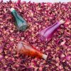 3 bottles of syrup on rose petals