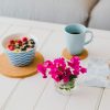 A bowl of overnight oats and fruit on a white table with pink flowers