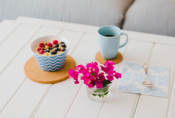A bowl of overnight oats and fruit on a white table with pink flowers