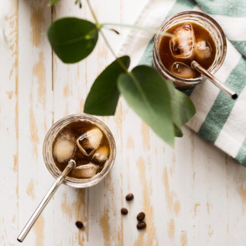 2 iced drinks on a wood table top with metal straws