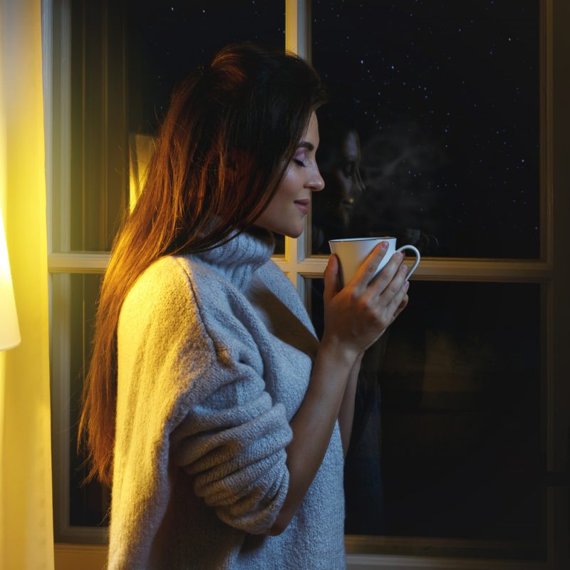 Woman drinking from a coffee cup in evening