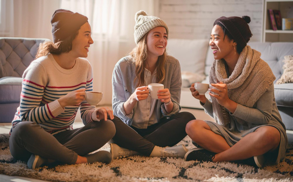 Friends sitting on the floor with lattes talking and laughing