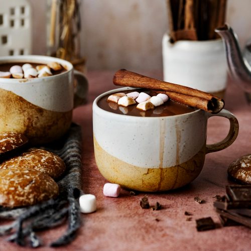 clay cups with hot chocolate, marshmallows and cinnamon sticks