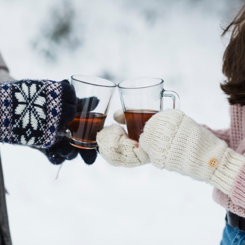 2 people outside with hot tea in clear glasses