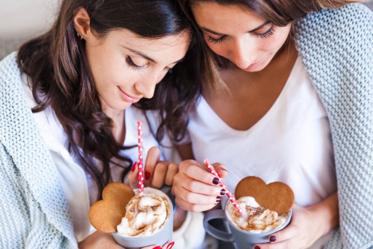 2 friends enjoying a hot chocolate with sugar cookies in the shape of a heart