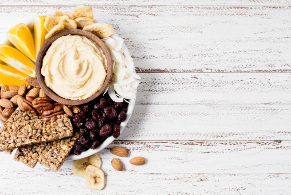 plate of granola, nuts and fruit with bowl of yogurt