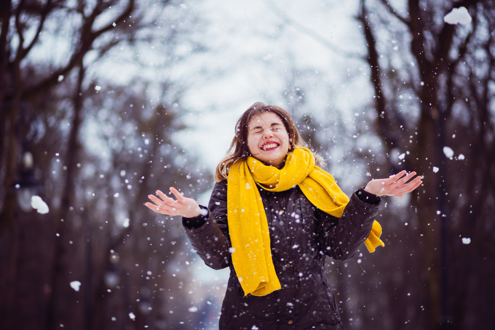 Woman with a yellow scarf smiling in the snow
