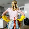 Women with hands on hips and yellow cleaning gloves looking at a messy room
