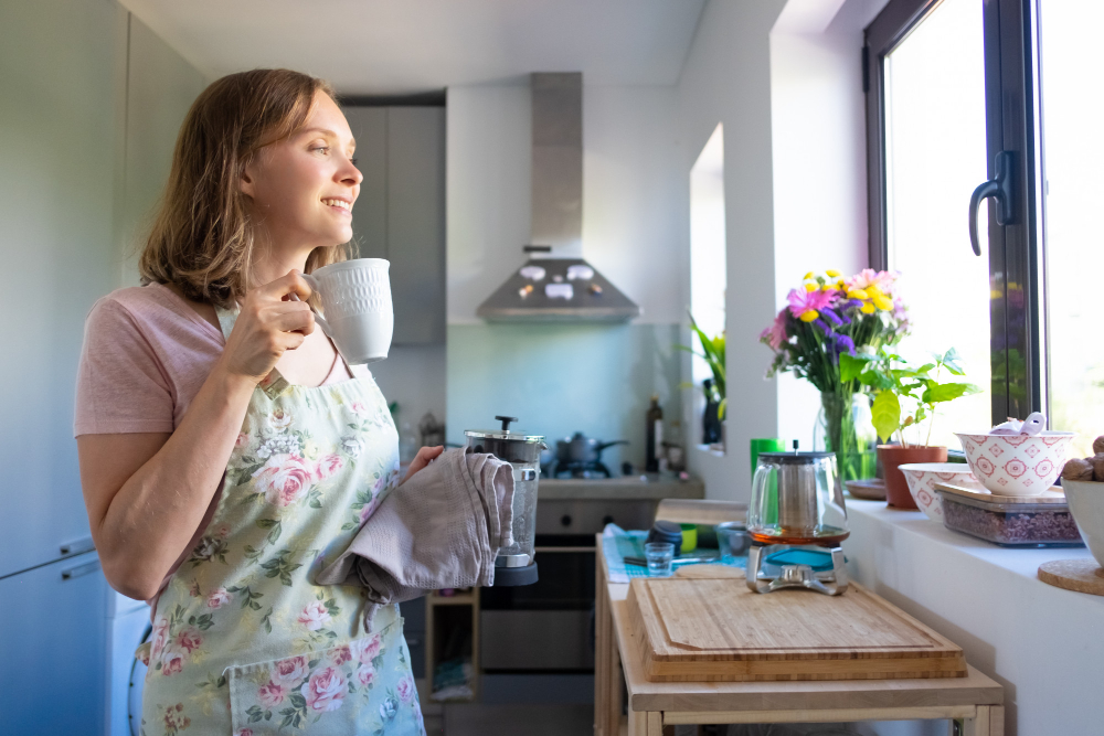 Woman wearing an apron in the kitchen cleaning and smiling