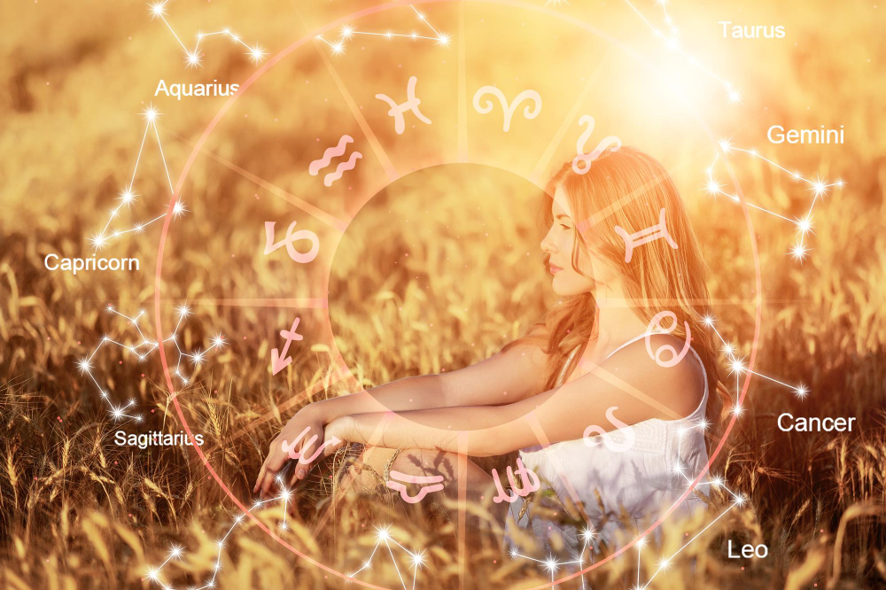 woman sitting in a field with zodiac illustrations around