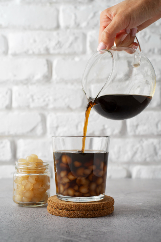 Someone pouring ice tea from a glass pitcher