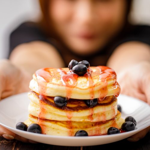 Close up of stack of pancakes with blueberries and syrup
