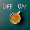 A coffee cup on a chalkboard with the words written in chalk off and on