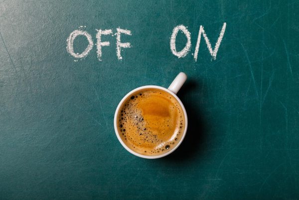 A coffee cup on a chalkboard with the words written in chalk off and on