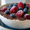 Overnight oats with a chocolate shell and fresh berries in a white bowl