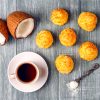 Coconut shell on a table with coconut muffins and a cup of coffee