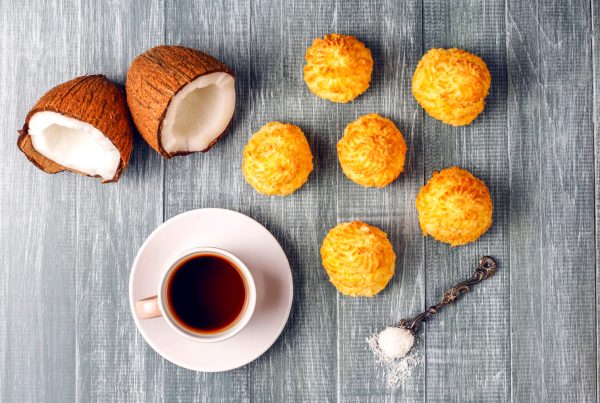 Coconut shell on a table with coconut muffins and a cup of coffee