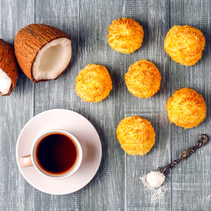 Coconut shell on a table with coconut muffins and a cup of coffee